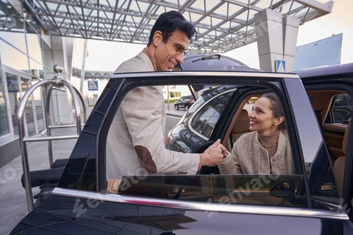 Preview: Male in glasses taking woman hand while she leaving car