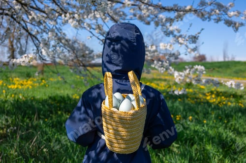 Preview: Child carries a woven basket with Easter eggs against a backdrop of blooming spring nature
