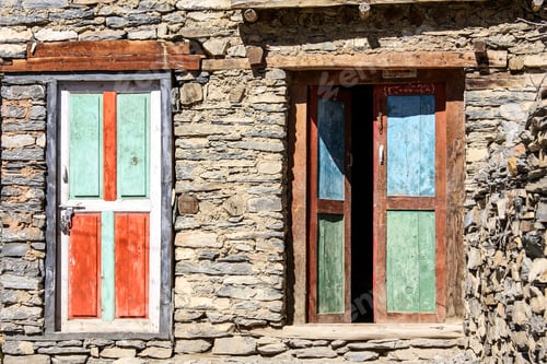 Preview: Multicolour red orange turquoise blue green distressed wooden shutters on stone house near Manang,
