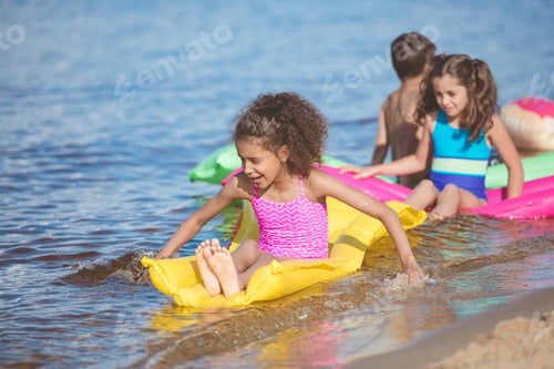 Preview: multicultural girls in swimsuits swimming on inflatable mattresses