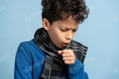 Preview: Portrait of unhappy little boy with scarf coughs isolated on blue background. Health care concept