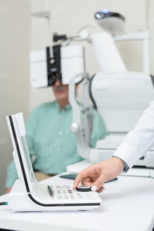 Preview: Hand of young contemporary ophthalmologist turning knob on examination equipment
