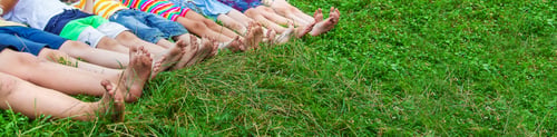 Preview: Children's feet lie on the grass. Selective focus.