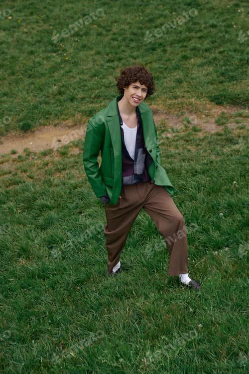 Preview: Young handsome student enjoys a refreshing walk on lush green grass in a serene outdoor setting