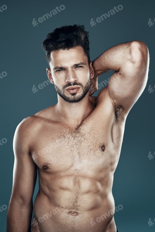 Preview: Handsome young shirtless man looking at camera while standing against grey background