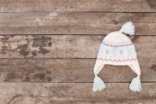 Preview: Warm knitted hat on rustic wooden surface ready for winter adventures