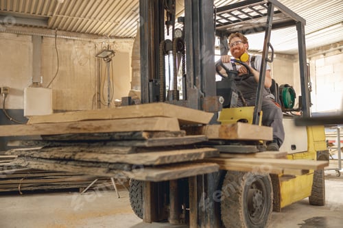 Preview: Male carpenter at wooden sawmill warehouse is loading with loader wooden board