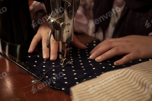 Preview: A woman's hands sew a piece of fabric with a sewing machine.