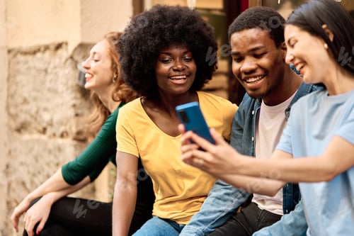 Preview: Happy multiethnic group of friends using the mobile outdoors
