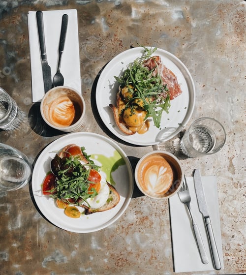 Preview: Morning brunch plates with coffee latte and a flat white at a hip and quirky local cafe