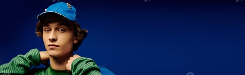 Preview: Young man exudes modern charm in vibrant attire against a striking blue backdrop