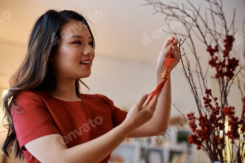 Preview: Happy woman enjoying in decorating her home for Chinese New Year celebration.