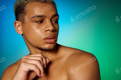 Preview: Muscular young man posing with dyed hair in a vibrant studio setting