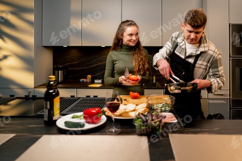Preview: young couple in love in beautiful kitchen preparing dinner together happy relationship