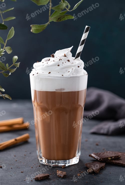 Preview: Hot chocolate with whipped cream and chocolate pieces and cinnamon in a glass on a dark background