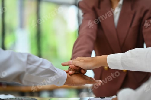 Preview: Businesspeople stacking hands over each other at meeting showing team unity, solidarity and teamwork