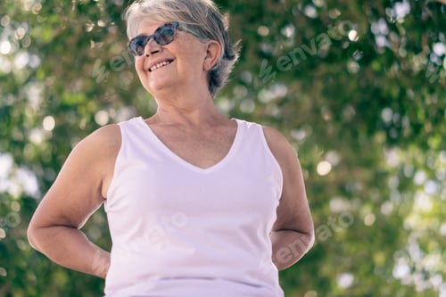 Preview: Beautiful senior woman gray-haired standing in outdoor public park smiling