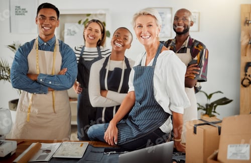 Preview: Group of five cheerful diverse clothing designers standing with their arms crossed in a shop at wor