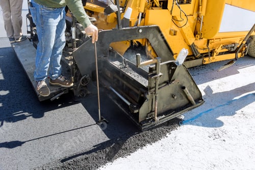 Preview: A steam roller and an asphalt paver machine are used during the construction of a new road as part