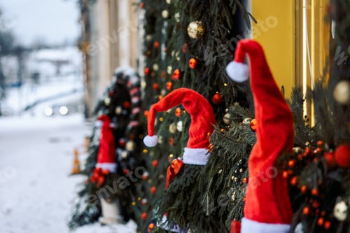 Preview: Abstract winter Christmas background with red santa hats, snow, fir branches and lights. Beautiful