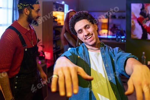 Preview: Young Man Smiling and Dancing at House Party with Friends