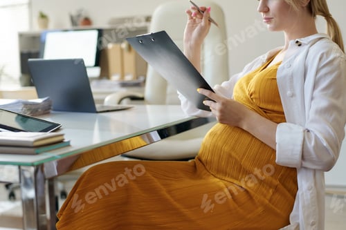 Preview: Pregnant woman filling documents in office