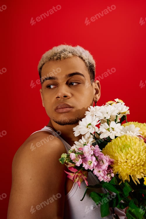 Preview: Young man with dyed hair poses in trendy attire surrounded by vibrant flowers