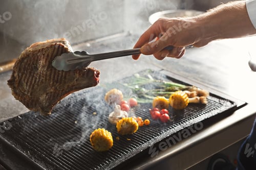 Preview: Chef cooking juicy beef steak at restaurant kitchen
