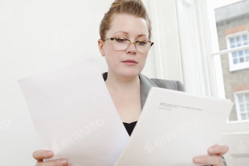 Preview: Businesswoman reading papers at desk