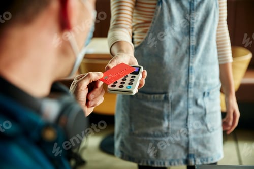 Preview: Woman holding contactless payment terminal for a customer paying by card