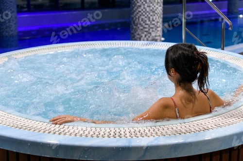 Preview: Rear view of woman relaxing in hot tub in spa and wellness resort.