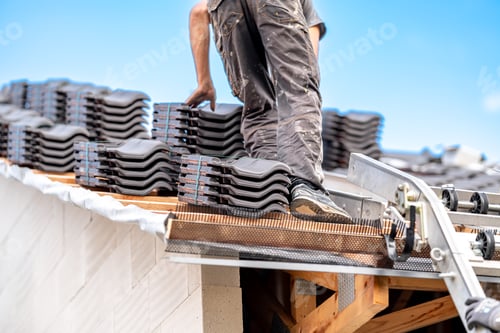 Preview: contractor builder laying fired ceramic tiles on the roof