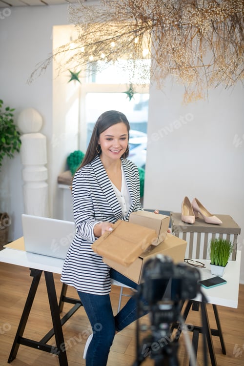 Preview: Positive young blogger holding presents for her followers