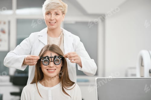 Preview: Frontview of young girl is sitting during vision checking with skilled oculist