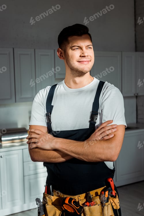Preview: sunshine on cheerful installer in overalls standing with crossed arms