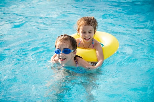 Preview: Two young smiling girls in a swimsuit bathes play in a pool.