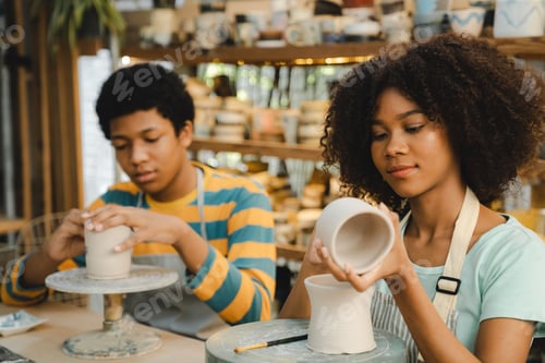 Preview: Creative afro American young woman artist molding clay by hand finger on pottery wheel