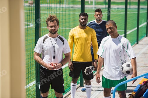 Preview: multicultural soccer team and referee standing on stadium before start of match