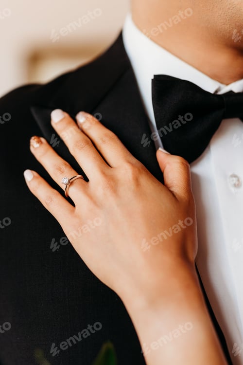 Preview: Vertical shot of the hand of the bride with the marriage ring holding her husband on the wedding day