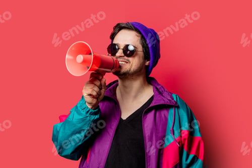 Preview: Funny guy in 80s style jacket and sunglasses holds megaphone on red backgorund