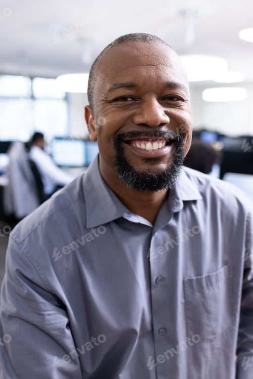 Preview: Happy african american businessman looking at camera in office