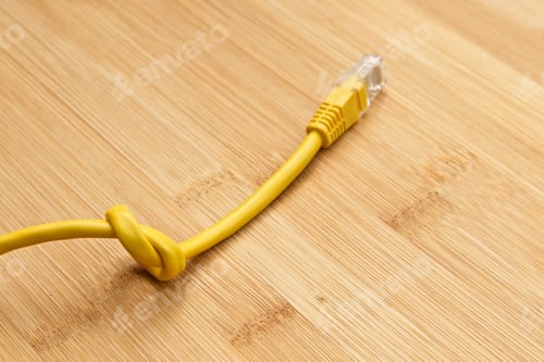 Preview: High angle shot of a knotted yellow cable on a wooden surface