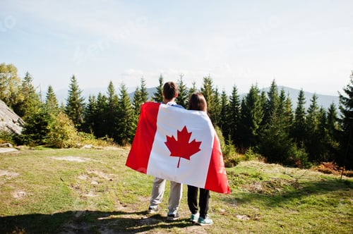 Preview: Happy Canada Day. Couple with large Canadian flag celebration in mountains.