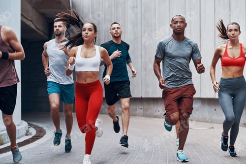 Preview: Group of young people in sports clothing jogging while exercising outdoors