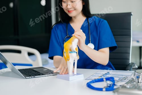 Preview: Confident young Asian female doctor in white medical uniform sit at desk working on computer.