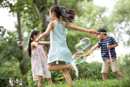 Preview: Three Chinese children blowing bubbles on grass