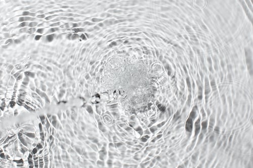 Vista previa: Patrón ondulado de salpicaduras de agua con una textura de superficie líquida cristalina.