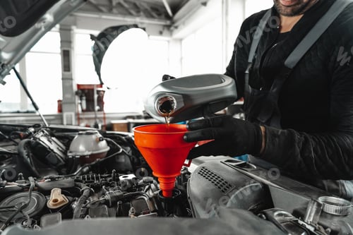 Preview: Close up of car service worker pouring new oil into car engine
