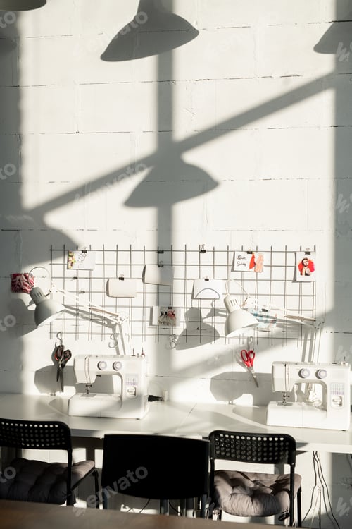Preview: Workplace of contemporary tailor or seamstress with table with lamps, sewing machines and others