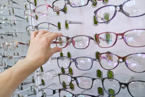 Preview: Showcase with glasses in the store, hand choosing glasses